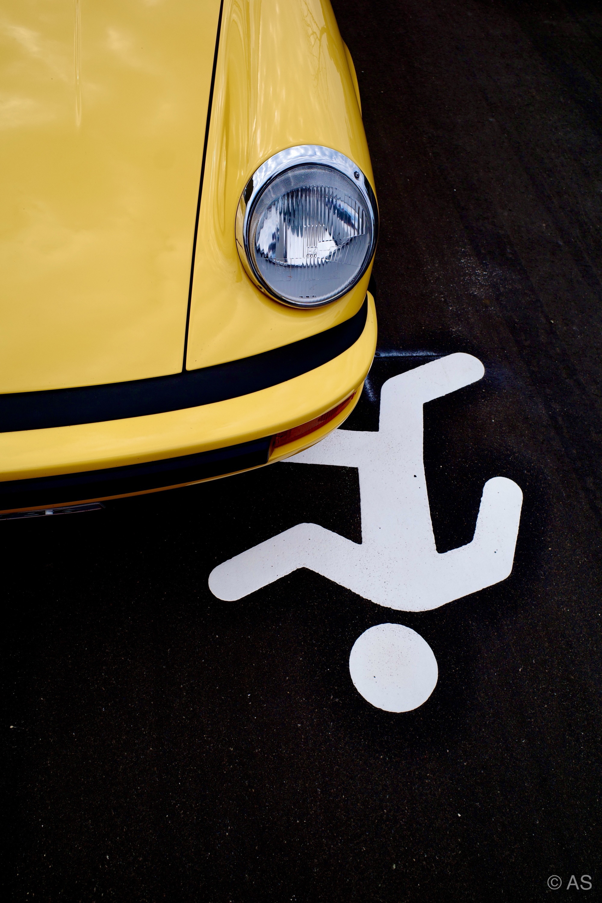 Yellow sports car positioned over a pedestrian crossing sign